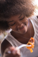 Image showing a young African American woman eating pasta