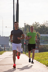 Image showing Two young men jogging through the city