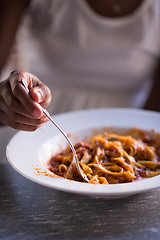 Image showing a young African American woman eating pasta