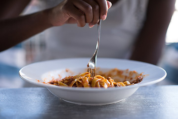 Image showing a young African American woman eating pasta