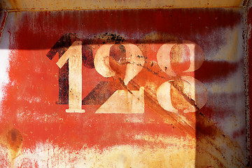 Image showing old rusty painted metal wall with numbers