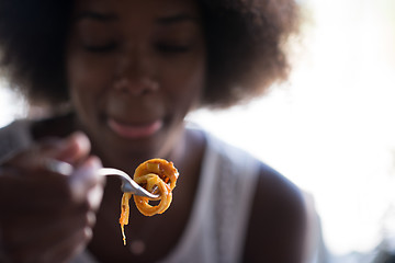 Image showing a young African American woman eating pasta