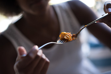 Image showing a young African American woman eating pasta