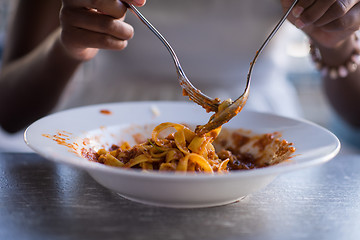 Image showing a young African American woman eating pasta