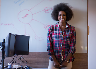 Image showing African American woman writing on a chalkboard in a modern offic