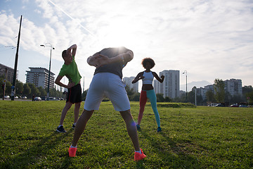 Image showing multiethnic group of people stretching in city park