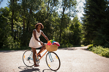 Image showing pretty young african american woman riding a bike in forest