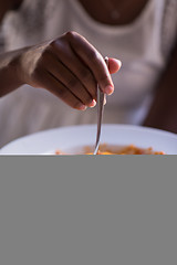 Image showing a young African American woman eating pasta