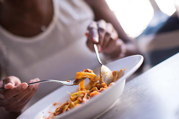 Image showing a young African American woman eating pasta