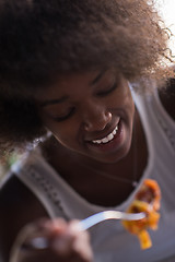 Image showing a young African American woman eating pasta