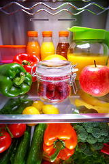 Image showing Fresh raspberries in a glass jar on a shelf open refrigerator