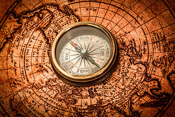 Image showing Vintage compass lies on an ancient world map.