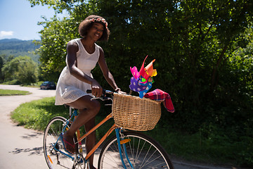 Image showing pretty young african american woman riding a bike in forest