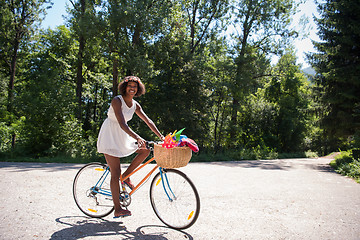 Image showing pretty young african american woman riding a bike in forest