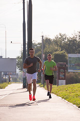 Image showing Two young men jogging through the city