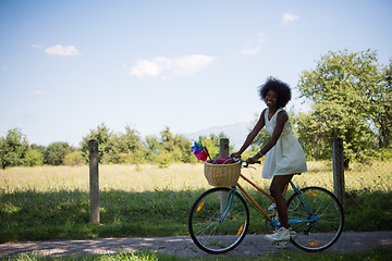 Image showing pretty young african american woman riding a bike in forest