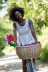 Image showing pretty young african american woman riding a bike in forest