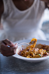 Image showing a young African American woman eating pasta