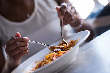 Image showing a young African American woman eating pasta