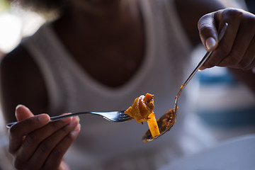 Image showing a young African American woman eating pasta