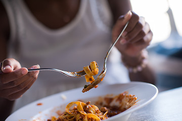 Image showing a young African American woman eating pasta