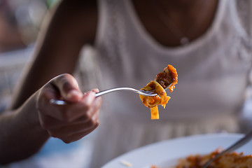 Image showing a young African American woman eating pasta