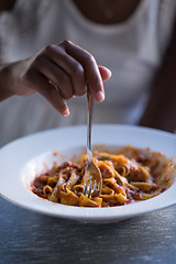 Image showing a young African American woman eating pasta