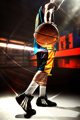 Image showing Silhouette view of a basketball player holding basket ball on black background