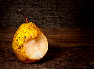 Image showing One bitten pear on a wooden table