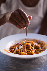 Image showing a young African American woman eating pasta