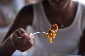 Image showing a young African American woman eating pasta