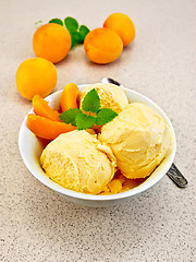 Image showing Ice cream apricot in white bowl on table with spoon