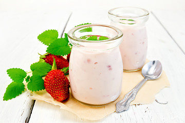 Image showing Yogurt with strawberries in jar on parchment and board