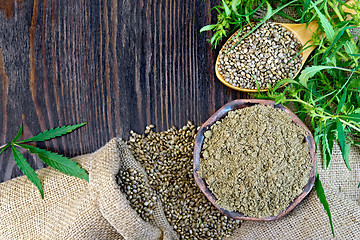 Image showing Flour hemp in bowl and seed in wooden spoon on board