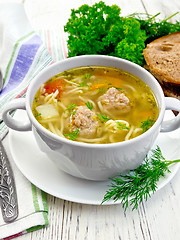 Image showing Soup with meatballs and noodles in white bowl on board