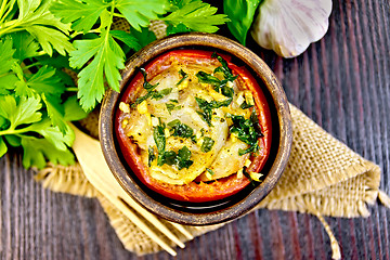 Image showing Fish baked with tomato in clay bowl on dark board top