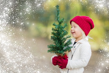 Image showing Baby Girl In Mittens Holding Small Christmas Tree with Snow Effe