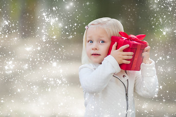 Image showing Baby Girl Holding Red Christmas Gift Outdoors with Snow Effect