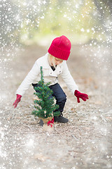 Image showing Girl In Red Mittens and Cap Near Small Christmas Tree with Snow 