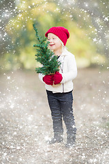 Image showing Baby Girl In Mittens Holding Small Christmas Tree with Snow Effe