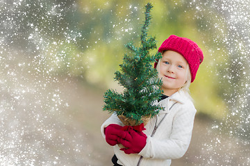 Image showing Baby Girl In Mittens Holding Small Christmas Tree with Snow Effe