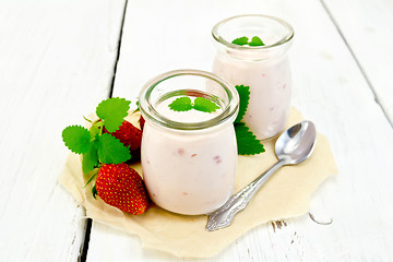 Image showing Yogurt with strawberries in jar on paper and board