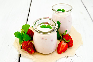 Image showing Yogurt with strawberries in jar on paper