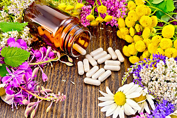 Image showing Capsules in open brown jar on dark board