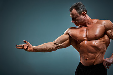 Image showing torso of attractive male body builder on gray background.