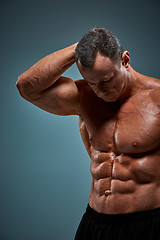 Image showing torso of attractive male body builder on gray background.