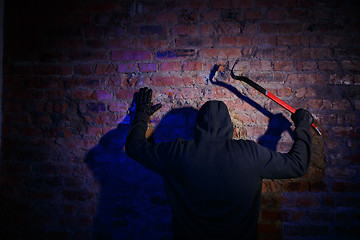 Image showing Gunman surrenders standing against wall