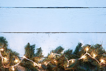 Image showing Christmas fir tree with yellow lightbulb on wooden board background