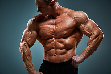 Image showing torso of attractive male body builder on gray background.