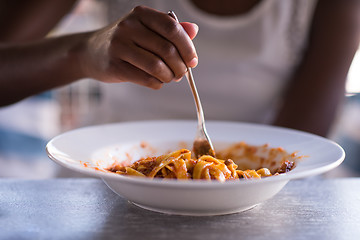 Image showing a young African American woman eating pasta